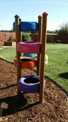 a wooden play structure with several different colored tires on it