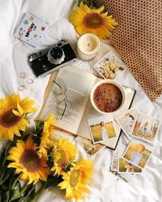 the sunflowers are next to an open book and some pictures on a bed