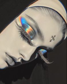 a woman's face with holographics and cross on her forehead, as if she is wearing an eyeliner