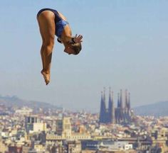 a woman diving into the water in front of a city