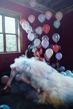 a woman sitting on the floor surrounded by balloons