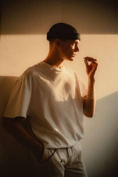 a man standing in front of a wall with his hand on his chin and looking off to the side