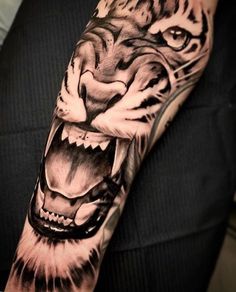 a tiger with its mouth open and it's teeth showing, on the arm