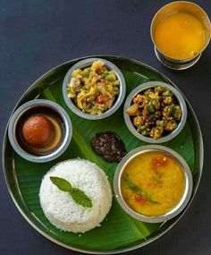 a plate full of different types of food on a black table with silver cups and sauces