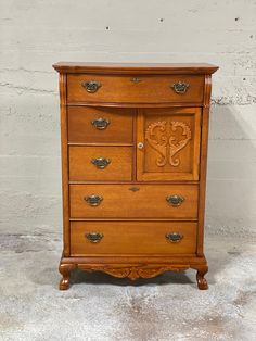 an old wooden dresser with ornate carvings on the top and bottom drawers, in front of a white brick wall