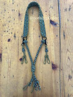 a close up of a necklace on a wooden surface with scissors hanging from it's end