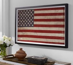 an american flag is hanging on the wall above a table with flowers and a book