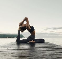 a woman is doing yoga on a dock