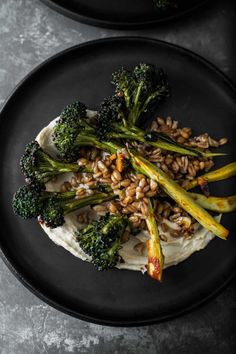 two black plates with broccoli, rice and other food items on top of them