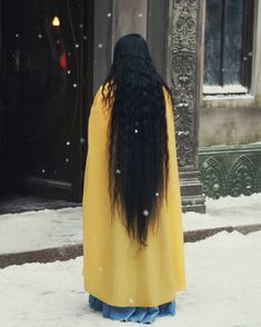 a woman with long black hair standing in the snow