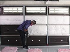 a man in plaid shirt and black pants working on garage doors with pink rugs