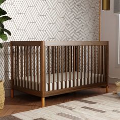 a baby crib in the corner of a room next to a potted plant