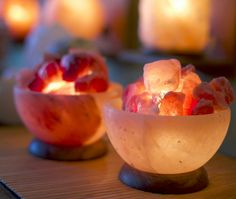 two bowls filled with ice and fruit sitting on top of a wooden table next to each other