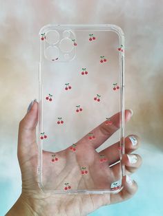 a hand holding up a clear case with cherries on it and red berries all over the back