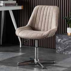 an office chair sitting on top of a gray floor next to a table with a potted plant