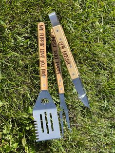 two spatulas and fork laying on the grass with words written on them next to each other