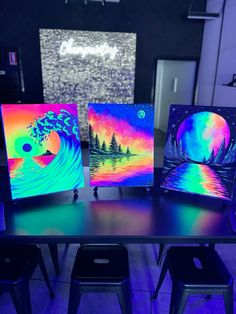 four different colored canvass sitting on top of a table in front of a wall