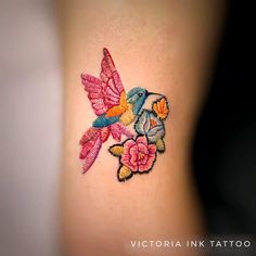 a colorful tattoo on the back of a woman's stomach with flowers and birds