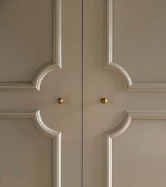 two white doors with gold knobs on each side and an arched design at the top