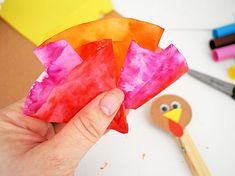 a hand holding a piece of paper with a turkey on it next to craft supplies