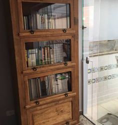 a book shelf with several books on it next to a bathtub and tiled floor