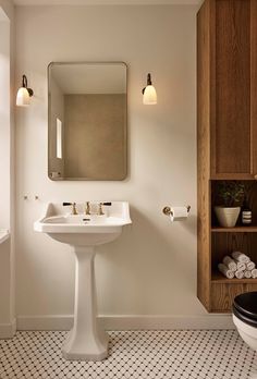 a white sink sitting under a bathroom mirror next to a black and white tiled floor