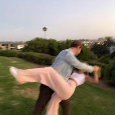 a man and woman are dancing in the grass outside with their arms around each other