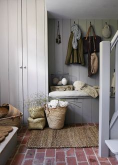 an entryway with baskets and coats hanging on the wall, next to a set of stairs