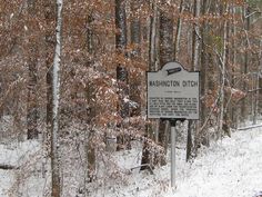 a sign in the middle of a snowy forest