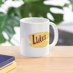 a white coffee mug with the words luke's on it sitting on a table