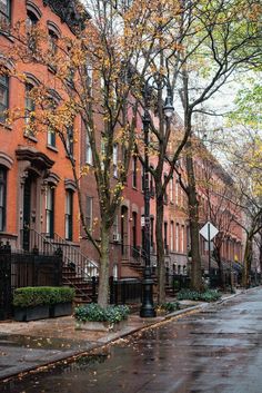 an empty city street in the fall with lots of leaves on the ground and tall brick buildings