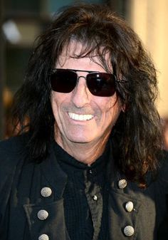 a man with long hair and sunglasses smiling