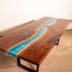 a table made out of wood with blue paint on the edge and a river running through it