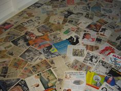 a pile of old newspaper sitting on top of a floor covered in pictures and advertisements