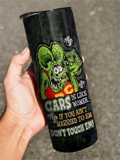 a person holding up a black bottle with green monsters on it