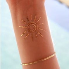 a woman's arm with gold tattoos on it