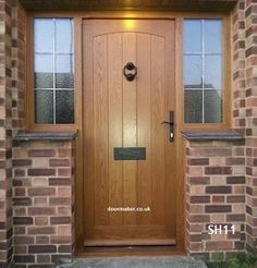 a wooden front door with two windows and brick pillars on the side of a house