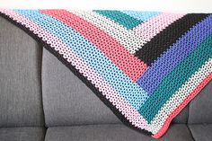 a crocheted blanket sitting on top of a gray couch