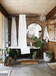 a bath room with a tub a mirror and plants