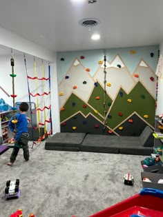 a child playing in a play room with climbing walls and toys on the floor,