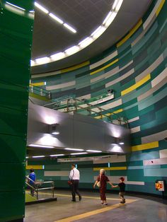 people are walking around in a large room with green and yellow stripes on the walls