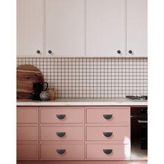 a kitchen with white cabinets and pink drawers on the counter top, along with a wooden cutting board