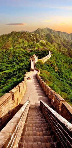 the great wall of china with stairs leading up to it and green hills in the background