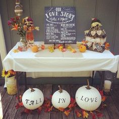 a table with pumpkins and fall decorations on it that read, fall in love