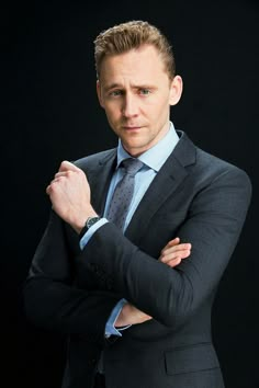 a man in a suit and tie posing for the camera with his arms crossed on his chest