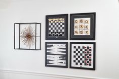 four framed art pieces hang on the wall next to a fireplace mantel with chess boards and checkers