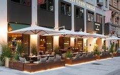 an outdoor restaurant with tables and umbrellas on the sidewalk in front of a building