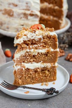 a piece of carrot cake on a plate with a fork in front of the slice