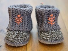 there is a pair of crocheted baby boots with orange stitchs on them