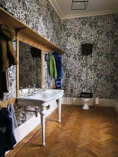 the bathroom is decorated in black and white floral wallpaper, with wood flooring